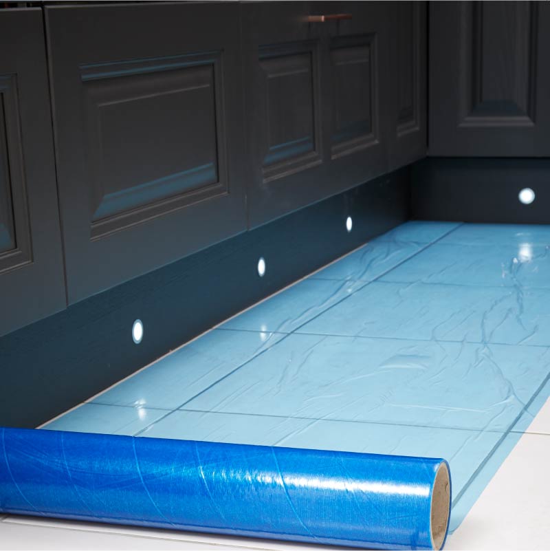 Roll of blue surface protection film on white kitchen tiles