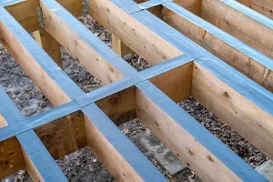 Close up of timber joists from a garden decking subframe with black deck tape protecting the surfaces from water.