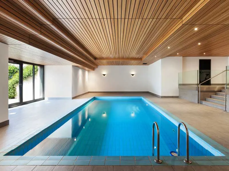 Tranquil indoor swimming pool with white walls and wooden ceiling
